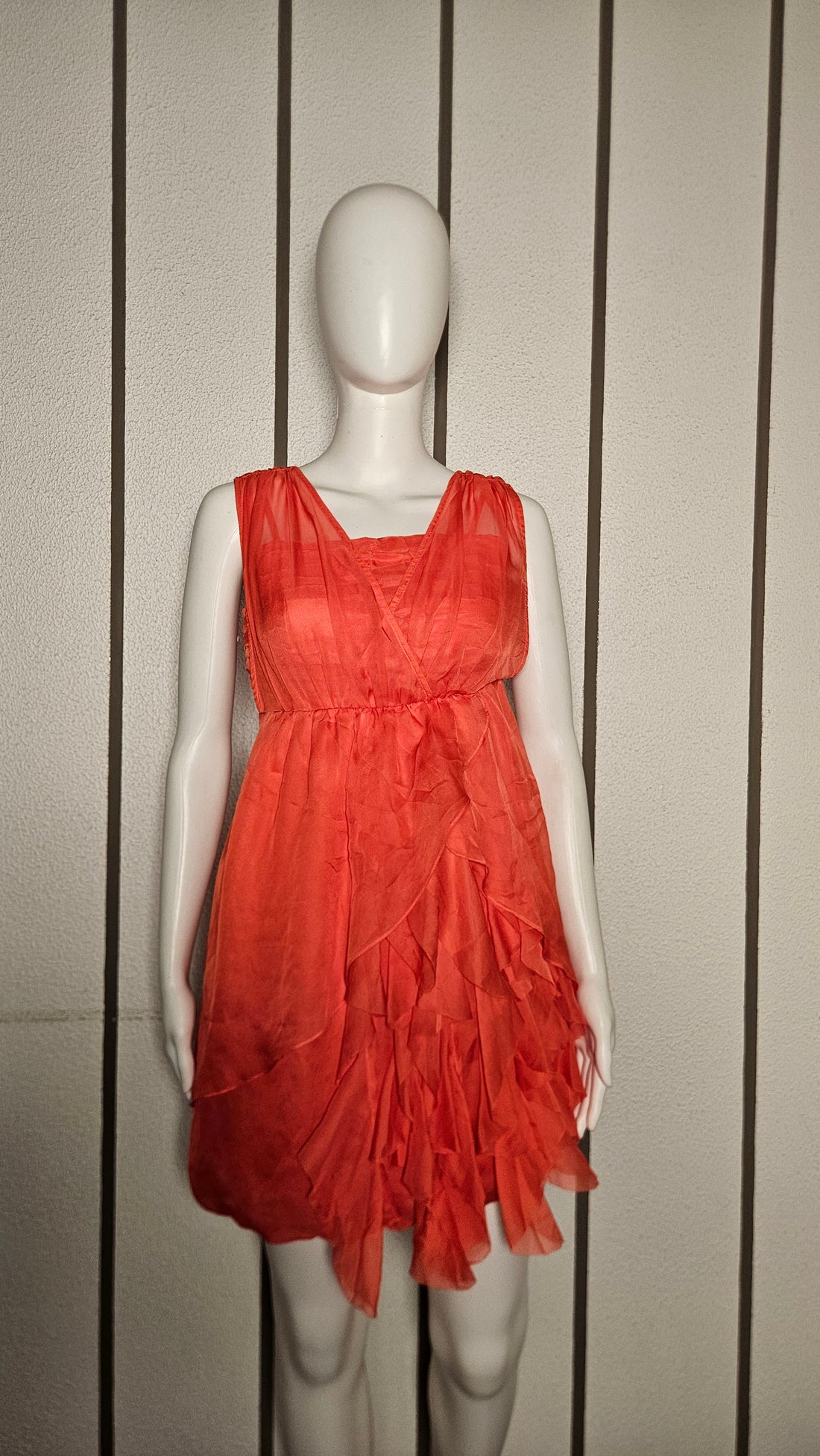 This fiery orange sleeveless mini dress features a plunging V-neckline and a tiered ruffle skirt for a fun
